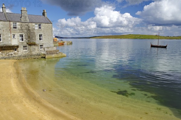 A quiet shore with an old building and a Viking ship in the water, crime series, Shetland Islands, Scotland, United Kingdom