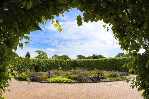 View of flower roundabout Lindenrund with bronze javelin thrower statue from 1937 by Ernst Seger in the background in front of hedge, Grugapark, Essen, North Rhine-Westphalia