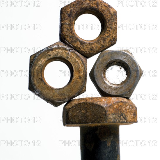 Multiple rusty nuts are stacked around a bolt, highlighting the effects of corrosion in a workshop environment. The metal parts show signs of aging and degradation from use