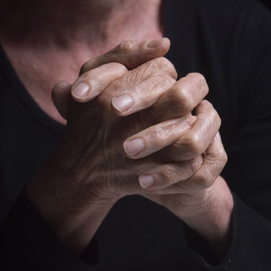 Fingers intertwined convey a sense of contemplation and tranquility. The soft lighting highlights the details of the hands, hinting at an introspective mood