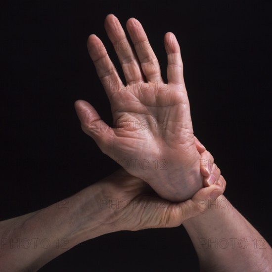 Two hands are featured in contrasting positions, highlighting the skin's texture and the grace of movement. The soft lighting enhances the details and shadows of the hands