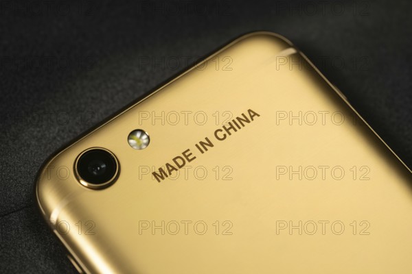Close-up of engraved Made in China text on the back of a shiny golden smartphone. Concept of globalization and offshore manufacturing. Generative ai, AI generated