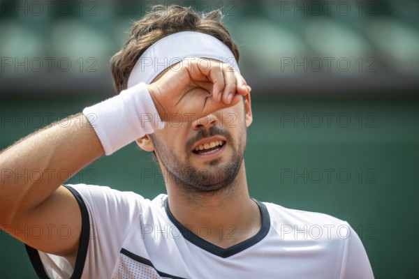 Man in tennis outfit wiping sweat from forehead. Concept for physical effort and athletic determination. Generative ai, AI generated
