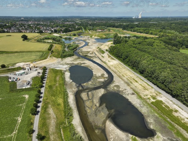 Dortmund, Castrop-Rauxel, North Rhine-Westphalia, Germany - River renaturalisation, renaturation of the Emscher, flood retention basin HRB Mengede. A new floodplain landscape is being created at the Emscher-Auen farm, expanding the area for flood protection during heavy rainfall and for biodiversity. The previously straightened Emscher is being given curves again and can meander through its new floodplain. Following the construction of a parallel sewer, the Emscher has been completely free of sewage since 2022. The river was previously an open, above-ground mixed water channel with rainwater and wastewater. At the back right, the Uniper coal-fired power plant Datteln 4 power station