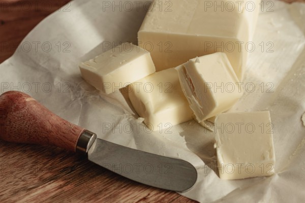 Butter briquette, on wrapping paper, wooden chopping board and butter knife, breakfast, rustic style, no people