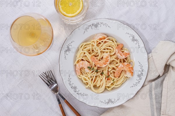 Pasta with shrimp and thyme, served on a white plate, with a glass of white wine, the table is set, Gourmet dinner, on a linen tablecloth, no people