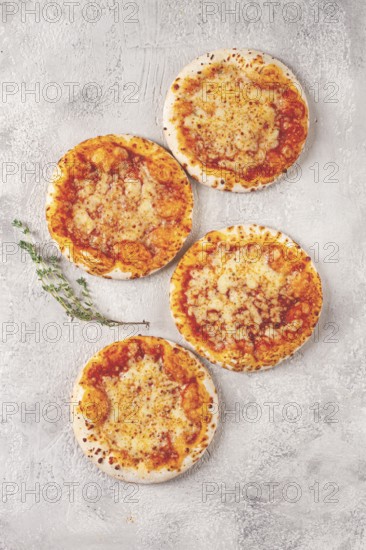Four pizzetta Margaritas, on a light grey surface, top view