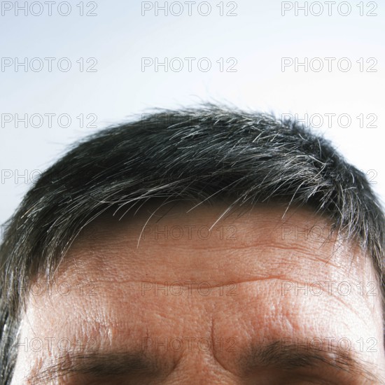 The view focuses on a man's forehead and hair, highlighting natural gray strands against a light background, creating a peaceful and calm atmosphere
