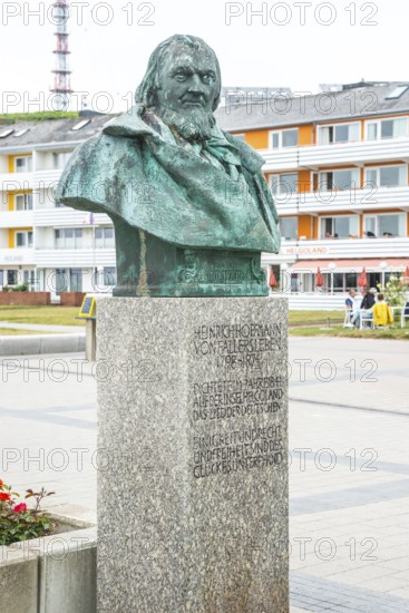 Sculpture, monument, bust, bronze bust of August Heinrich Hoffmann von Fallersleben, author of the later German national anthem, Das Lied der Deutschen, on a stone pedestal in front of modern, colourful buildings, writer, poet, Einigkeit und Recht und Freiheit, Kurpromenade Helgoland, Schleswig-Holstein, Germany