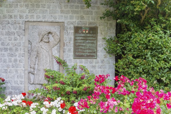 Monument, stone relief showing Jacob Andresen Siemens, founder of the seaside resort of Heligoland, fisherman, sailor with rain gear and rope, rope in hand, memorial plaque, flowery garden landscape, flower bed, spa promenade, Heligoland, Schleswig-Holstein, Germany