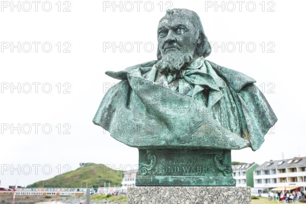 Close-up of the sculpture, monument, bust, bronze bust of August Heinrich Hoffmann von Fallersleben, author of the later German national anthem, The Song of the Germans, on a stone pedestal with a view of the sea in the background the lobster shacks, colourful, brightly coloured buildings, writer, poet, unity and justice and freedom, spa promenade Helgoland, Schleswig-Holstein, Germany