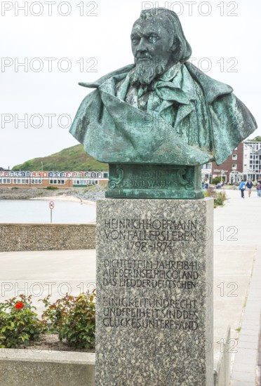 Sculpture, monument, bust, bronze bust of August Heinrich Hoffmann von Fallersleben, author of the later German national anthem, Das Lied der Deutschen, on a stone pedestal with a view of the sea in the background the North Sea and the lobster shacks, colourful buildings, writer, poet, unity and justice and freedom, spa promenade Helgoland, Schleswig-Holstein, Germany