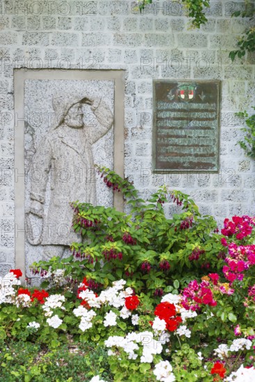 Monument, stone relief showing Jacob Andresen Siemens, founder of the seaside resort of Heligoland, fisherman, sailor with rain gear and rope, rope in hand, memorial plaque, flower bed, spa promenade, Heligoland, Schleswig-Holstein, Germany