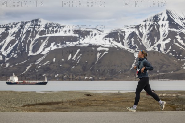 Marathon, runner in front of fjord with cargo ship, Adventtoppen, Longyearbyen, Spitsbergen, Svalbard