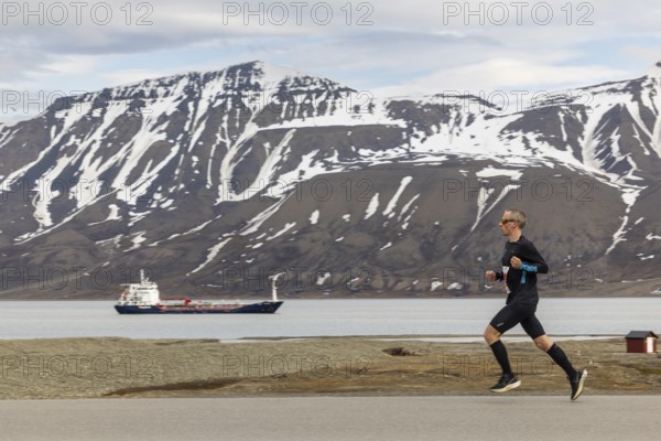 Marathon, runner in front of fjord with cargo ship, Longyearbyen, Spitsbergen, Svalbard