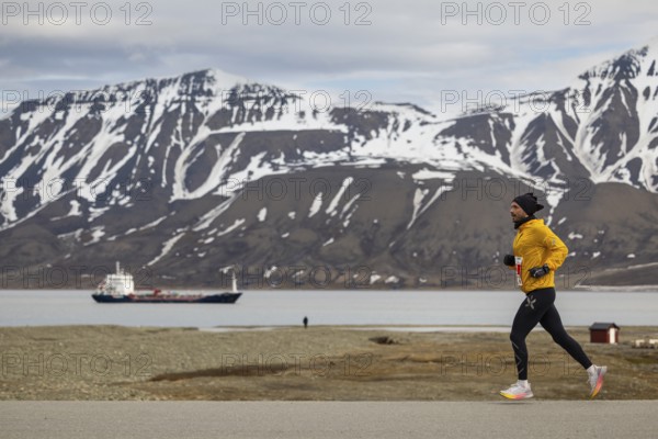 Marathon, runner in front of fjord with cargo ship, Adventtoppen, Longyearbyen, Spitsbergen, Svalbard