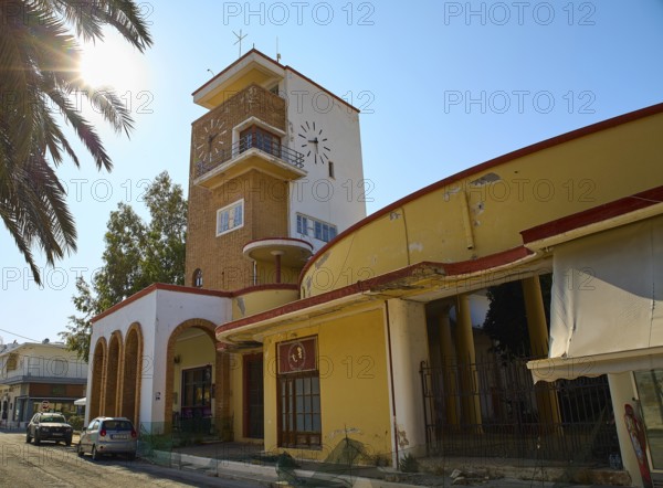 Market Hall, A building with a clock tower, surrounded by palm trees, under the sun and clear sky, Armando Bernabiti, Historicism, Rationalism, Art Deco, Rationalism, Rodolfo Petraco, Fascism, Portolago, Lakki, Leros, Dodecanese, Greek Islands, Greece