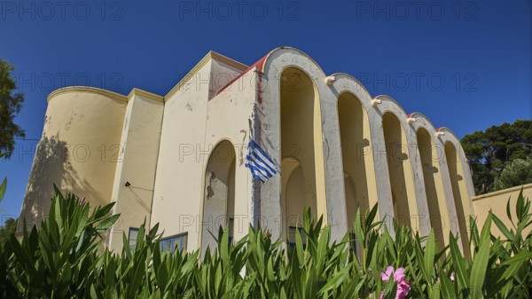 Primary school, Building with arches and Greek flag, surrounded by plants, Armando Bernabiti, Historicism, Rationalism, Art Deco, Rationalism, Rodolfo Petraco, Fascism, Portolago, Lakki, Leros, Dodecanese, Greek Islands, Greece
