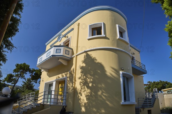 Modern yellow house with curves and balcony surrounded by trees, Armando Bernabiti, Historicism, Rationalism, Art Deco, Rationalism, Rodolfo Petraco, Fascism, Portolago, Lakki, Leros, Dodecanese, Greek Islands, Greece