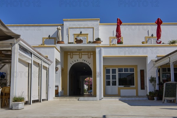 White building with entrance and decorative umbrellas on a terrace on a sunny day, Armando Bernabiti, Historicism, Rationalism, Art Deco, Rationalism, Rodolfo Petraco, Fascism, Portolago, Lakki, Leros, Dodecanese, Greek Islands, Greece