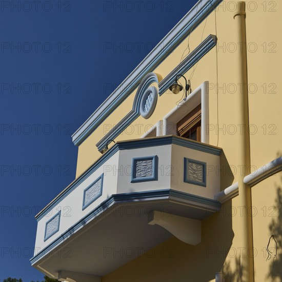Yellow building with decorative balcony in front of a clear blue sky, Armando Bernabiti, Historicism, Rationalism, Art Deco, Rationalism, Rodolfo Petraco, Fascism, Portolago, Lakki, Leros, Dodecanese, Greek Islands, Greece