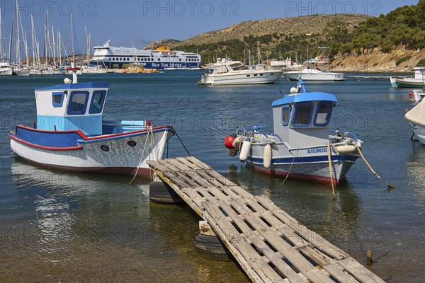 Two small boats on a jetty with a large ferry and yachts in the background, Lakki, Leros, Dodecanese, Greek Islands, Greece