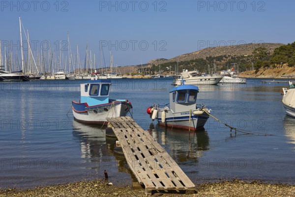Two small boats on a wooden jetty in a quiet harbour with sailing yachts, Lakki, Leros, Dodecanese, Greek Islands, Greece