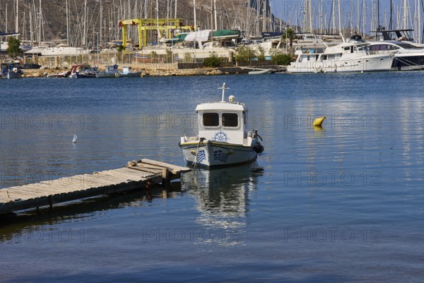 Small boat at the pier in a picturesque harbour with sailing yachts in the background, Lakki, Leros, Dodecanese, Greek Islands, Greece