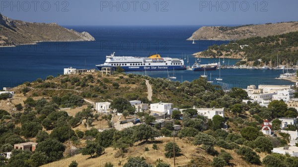 Large ferry in front of a coastal settlement on a hill with blue sea in the background, Lakki, Leros, Dodecanese, Greek Islands, Greece