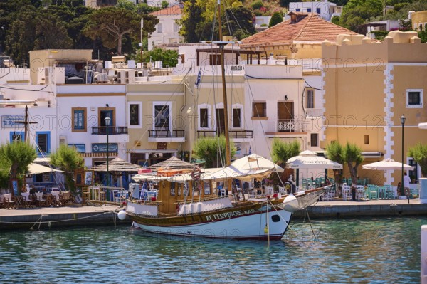 Traditional wooden boat in a lively harbour with adjoining restaurants, Lakki, Leros, Dodecanese, Greek Islands, Greece
