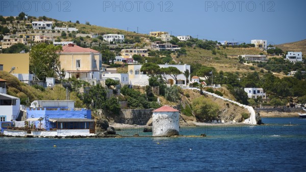 Charming houses and mill along a coastal road with green surroundings, Lakki, Leros, Dodecanese, Greek Islands, Greece