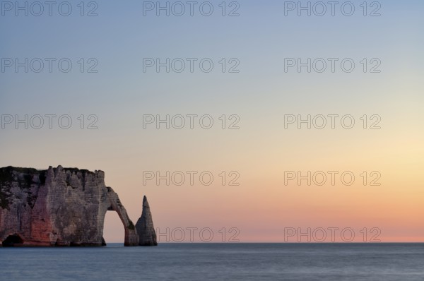 Rock arch Falaise or Porte d'Aval and rock needle Aiguille, illuminated, illuminated, Étretat, sea, steep coast, cliffs, chalk cliffs, alabaster coast, La Côte d'Albâtre, sunset, evening mood, atmospheric, Normandy, Seine-Maritime, France