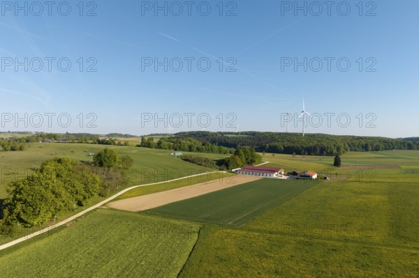 Farm, green fields stretch out under a blue sky, with wind turbines in the distance, near Westerheim, Swabian Alb, Baden-Württemberg, Germany