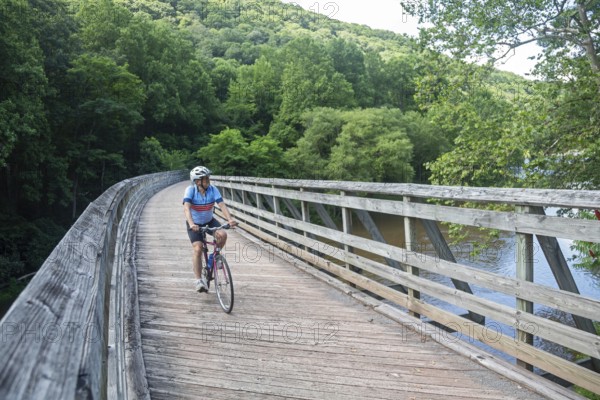 Marlinton, West Virginia - A bicyclist rides across a former railroad bridge over the Greenbrier River, now part of the Greenbrier River Trail. The biking and hiking trail, on the railbed of the former Chesapeake and Ohio Railway, runs 78 miles in eastern West Virginia