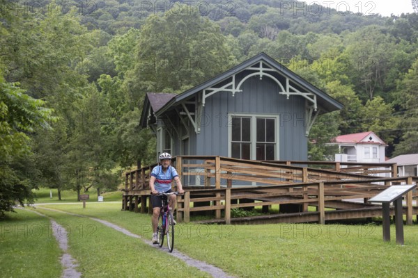 Clover Lick, West Virginia - A bicyclist rides past a restored train station on the Greenbrier River Trail. The biking and hiking trail, on the railbed of the former Chesapeake and Ohio Railway, runs 78 miles in eastern West Virginia
