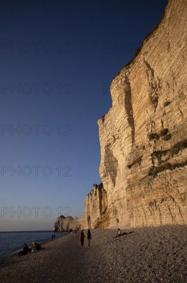 People on the beach, pebble beach, rock arch Falaise or Porte d'Amont, Étretat, sea, steep coast, cliffs, chalk cliffs, alabaster coast, La Côte d'Albâtre, evening mood, atmospheric, Normandy, Seine-Maritime, France