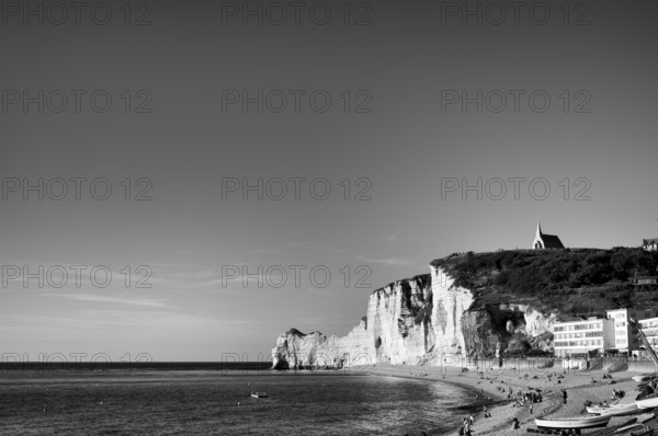 Rowing boat, boats lying on the beach, pebble beach, rock arch Falaise or Porte d'Amont, church Chapelle Notre Dame de la Garde, Étretat, sea, steep coast, cliffs, chalk cliffs, alabaster coast, La Côte d'Albâtre, black and white, Normandy, Seine-Maritime, France