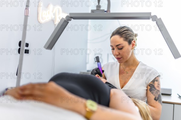 Beautician performing a professional permanent makeup treatment on a client's eyebrows, using a specialized device in a modern beauty salon