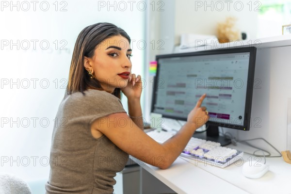 Beautician pointing at computer screen showing appointments calendar, managing schedule and bookings in a beauty salon
