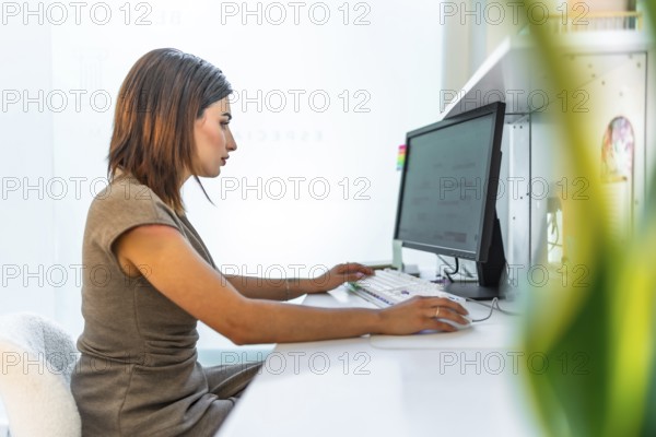 Beautician using a desktop computer, managing appointments and customer data in a bright and modern beauty salon