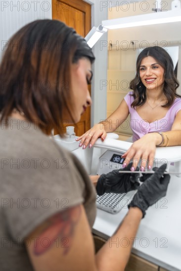 Beautician wearing black gloves attentively filing the nails of a smiling customer in a modern beauty salon, creating a relaxing experience