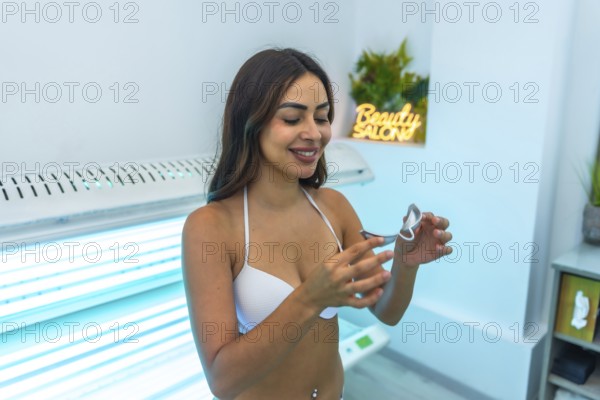 Client preparing for a uv tanning session, adjusting protective eyewear while getting ready in a beauty salon for a sunbed experience