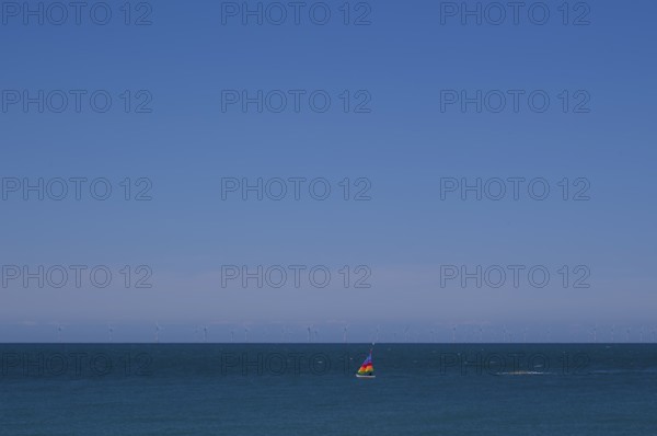 Sailboat, colourful sail, sailing on sea, sky, blue, behind offshore wind farm, wind turbines, Étretat, Normandy, Seine-Maritime, France
