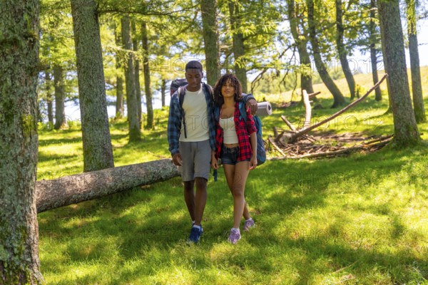 Young couple hiking through a lush forest, enjoying a summer trekking adventure filled with exploration, nature, and togetherness