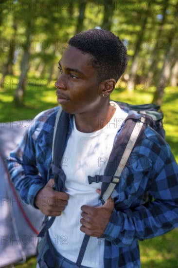 Young hiker adjusting backpack straps, preparing for an exciting journey through the lush forest, ready to embrace the great outdoors
