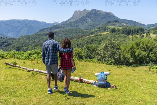 Couple admiring breathtaking mountain landscape during summer hike, enjoying the peace and beauty of nature