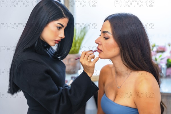 Professional makeup artist carefully applying lip liner on a client, enhancing her beauty in a salon setting