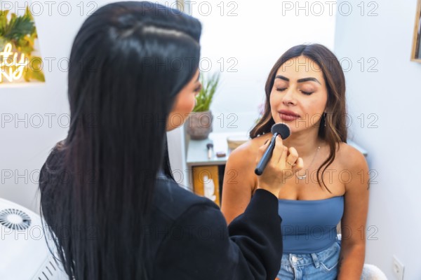 Beautician applying makeup on a client's face using a brush, enhancing her beauty in a professional salon environment
