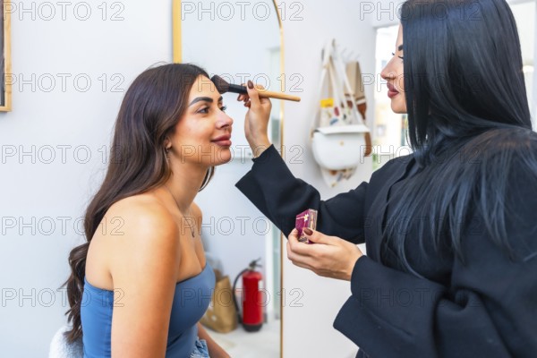 Professional makeup artist applying foundation on a client's face using a brush, enhancing her beauty in a salon environment