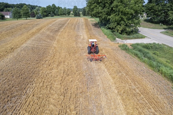 Wayland, Michigan - A farmer uses a rotary tedder to aerate his crop. A tedder spreads out hay or straw to allow quicker drying before baling